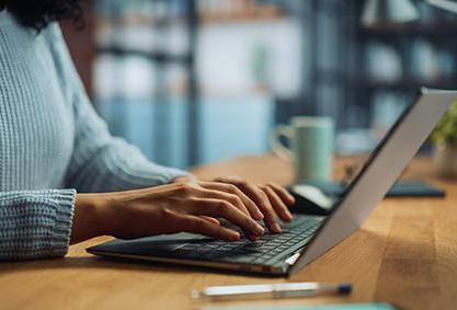 Image shows a pair of hands typing on a laptop.